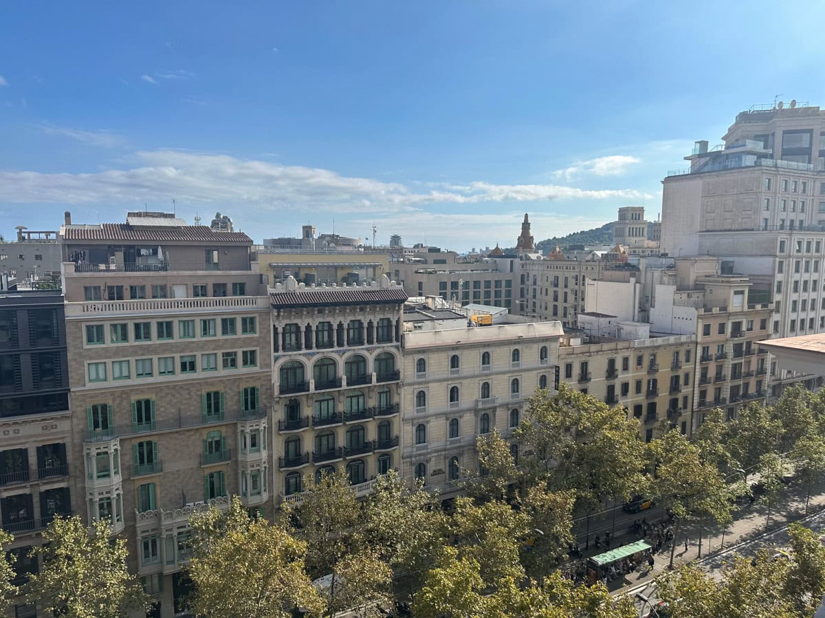 Residential buildings in Barcelona surrounded by trees as seen from a rooftop.