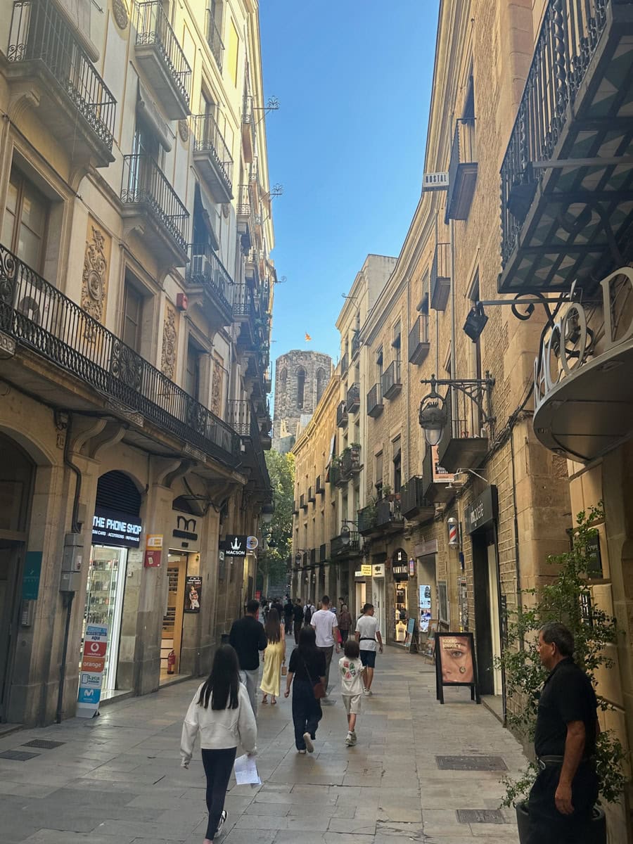 People walking on an alley between buildings in Barcelona.