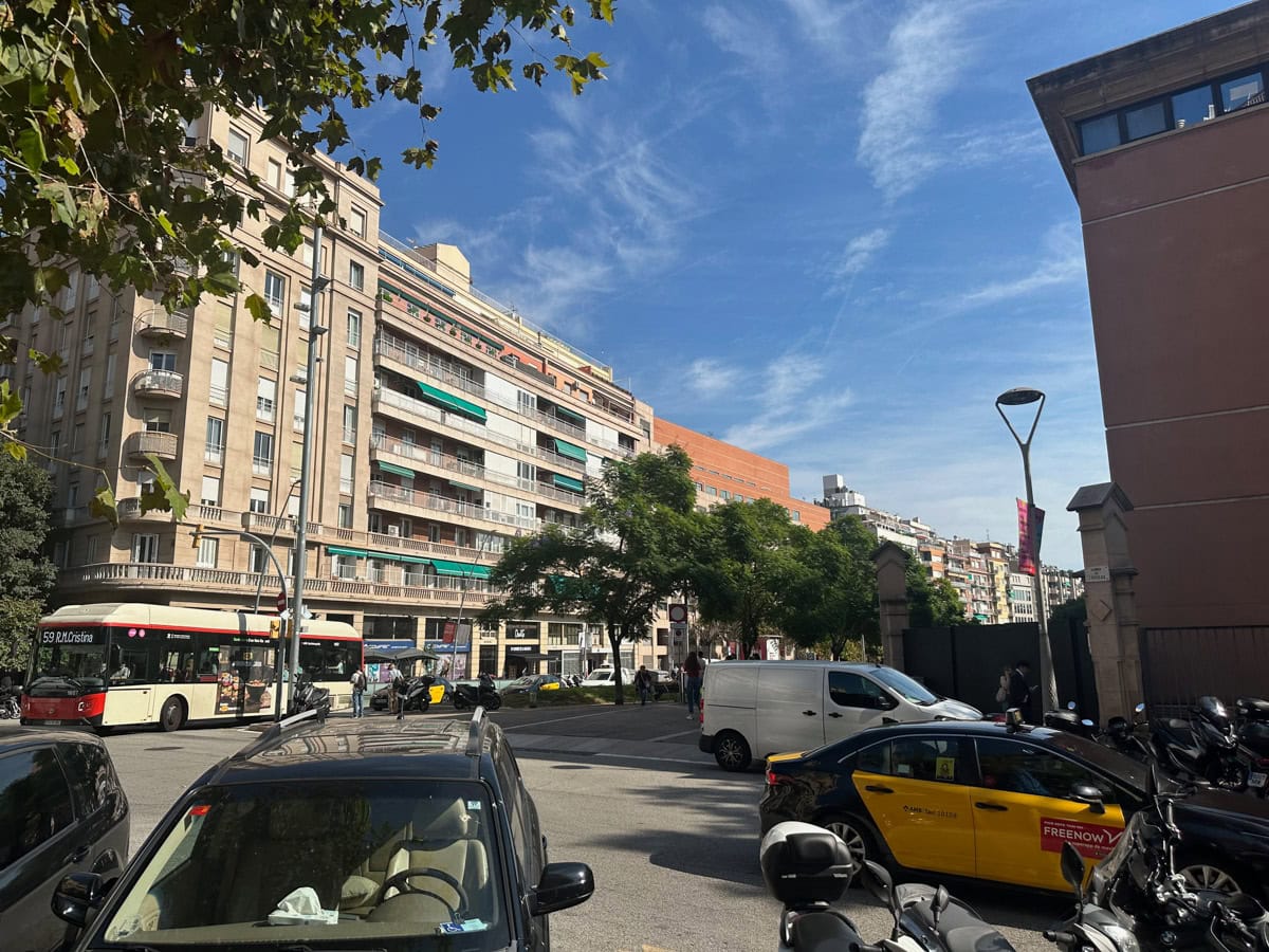 Vehicles parks and on the road with a building in the background in Spain.