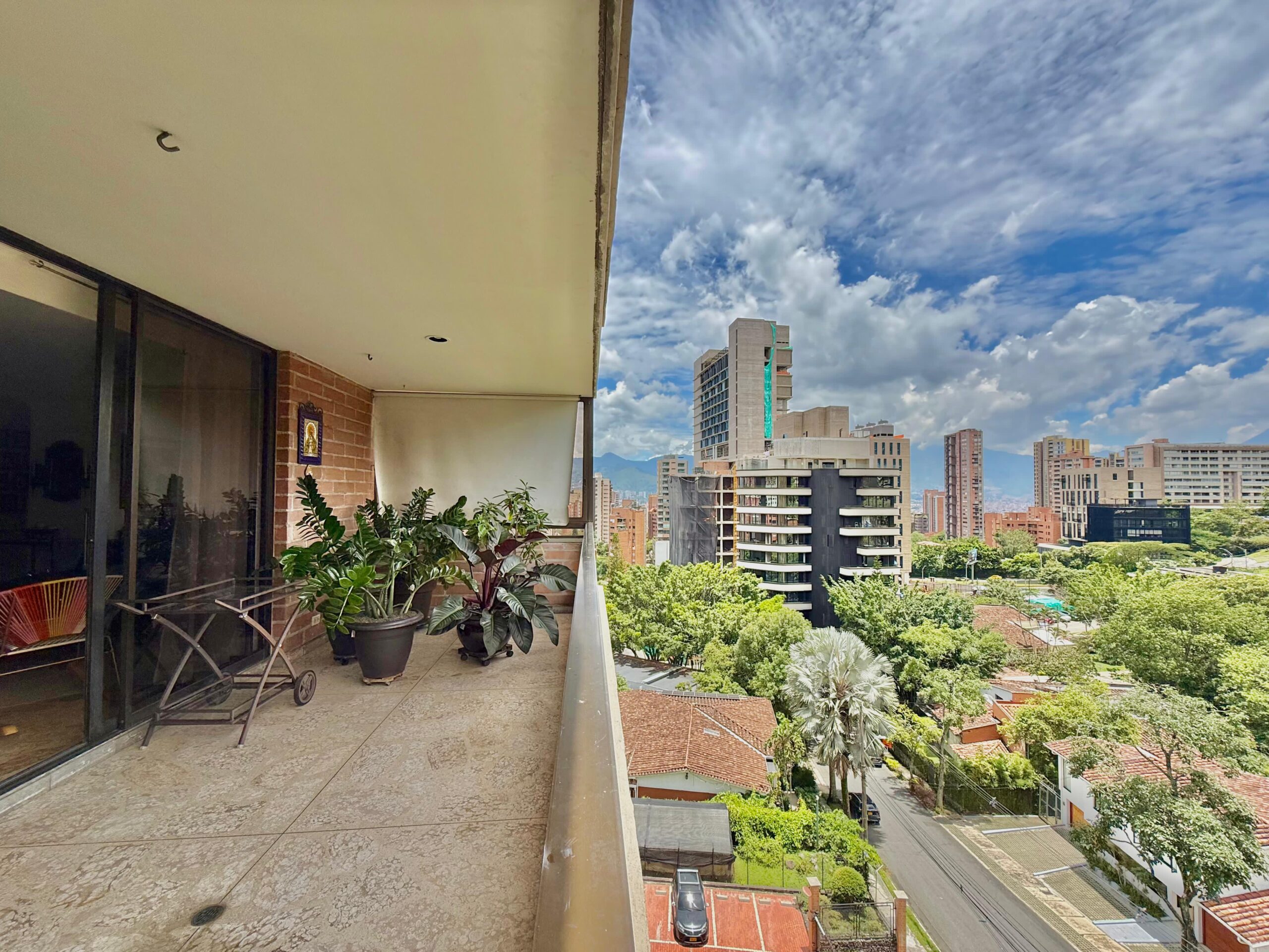 View from a balcony of an apartment in Medellin with a view of streets lined with trees and houses and blocks of flats