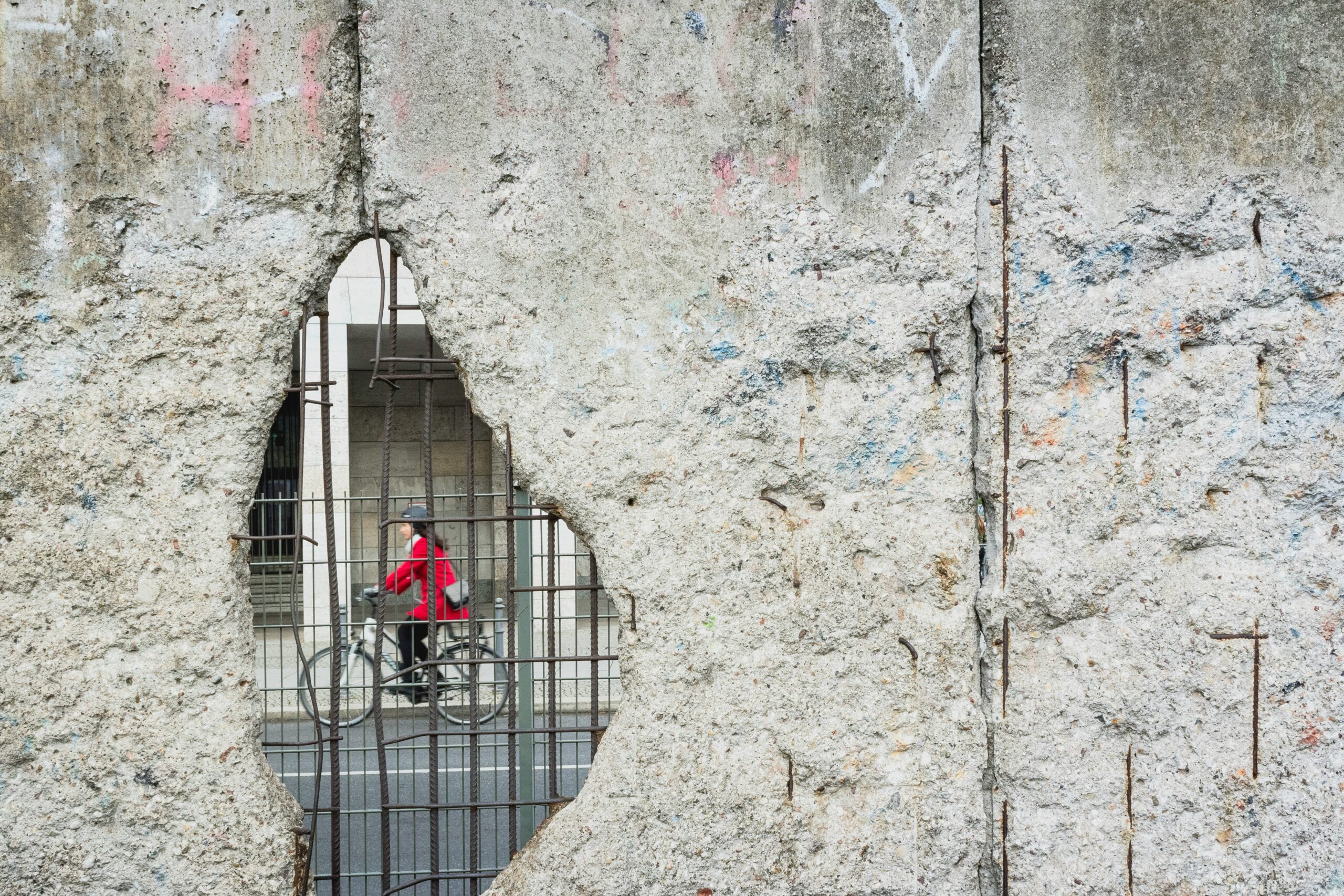 Woman cycling seen through a gap in the Berlin Wall