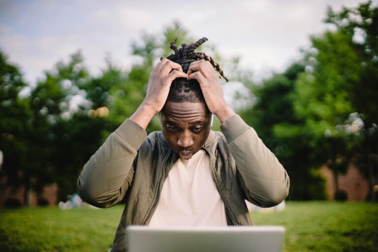 African American man confused at laptop in park