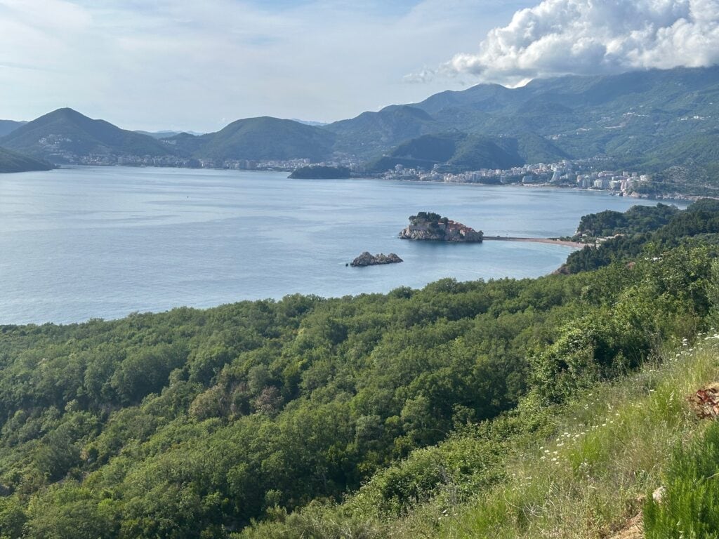 View from higher up of Sveti Stefan and surrounding area, including sea and mountains, in Montenegro