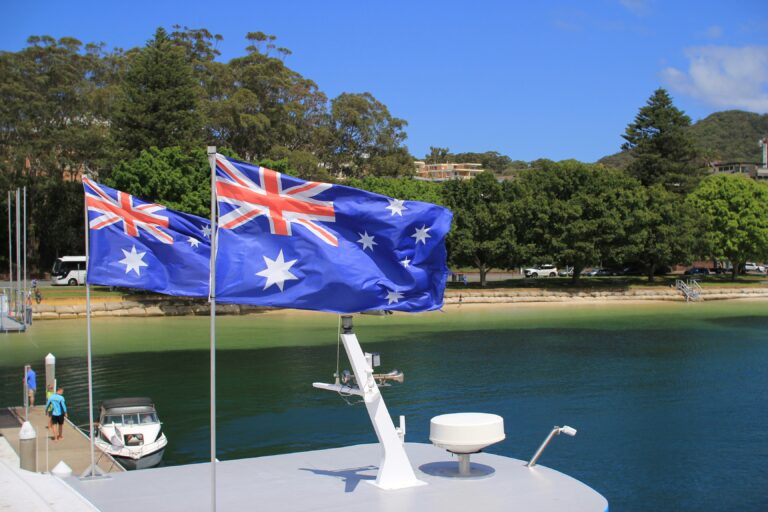 Australian flag on top of a boat with trees and green in the background