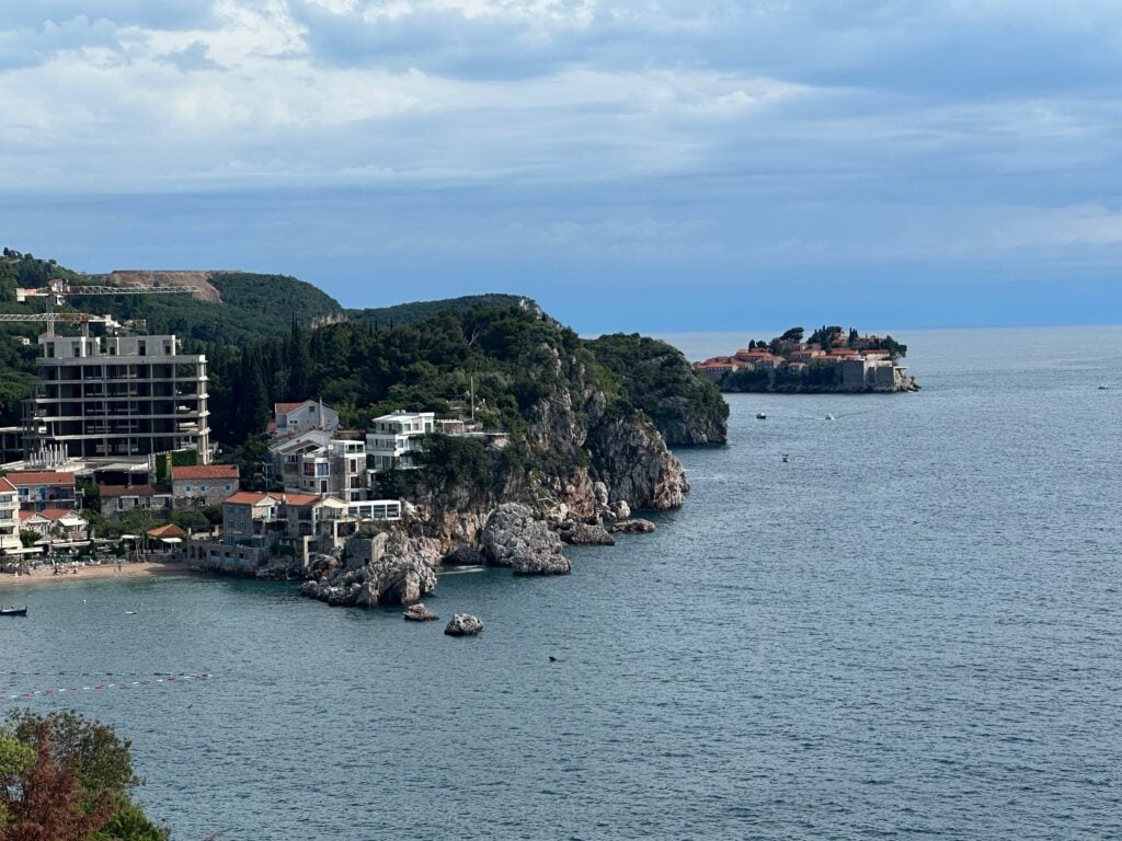 View of the coastline near Budva, Montenegro with a view of the hills and some residential blocks of flats and Sveti Stefan in the distance