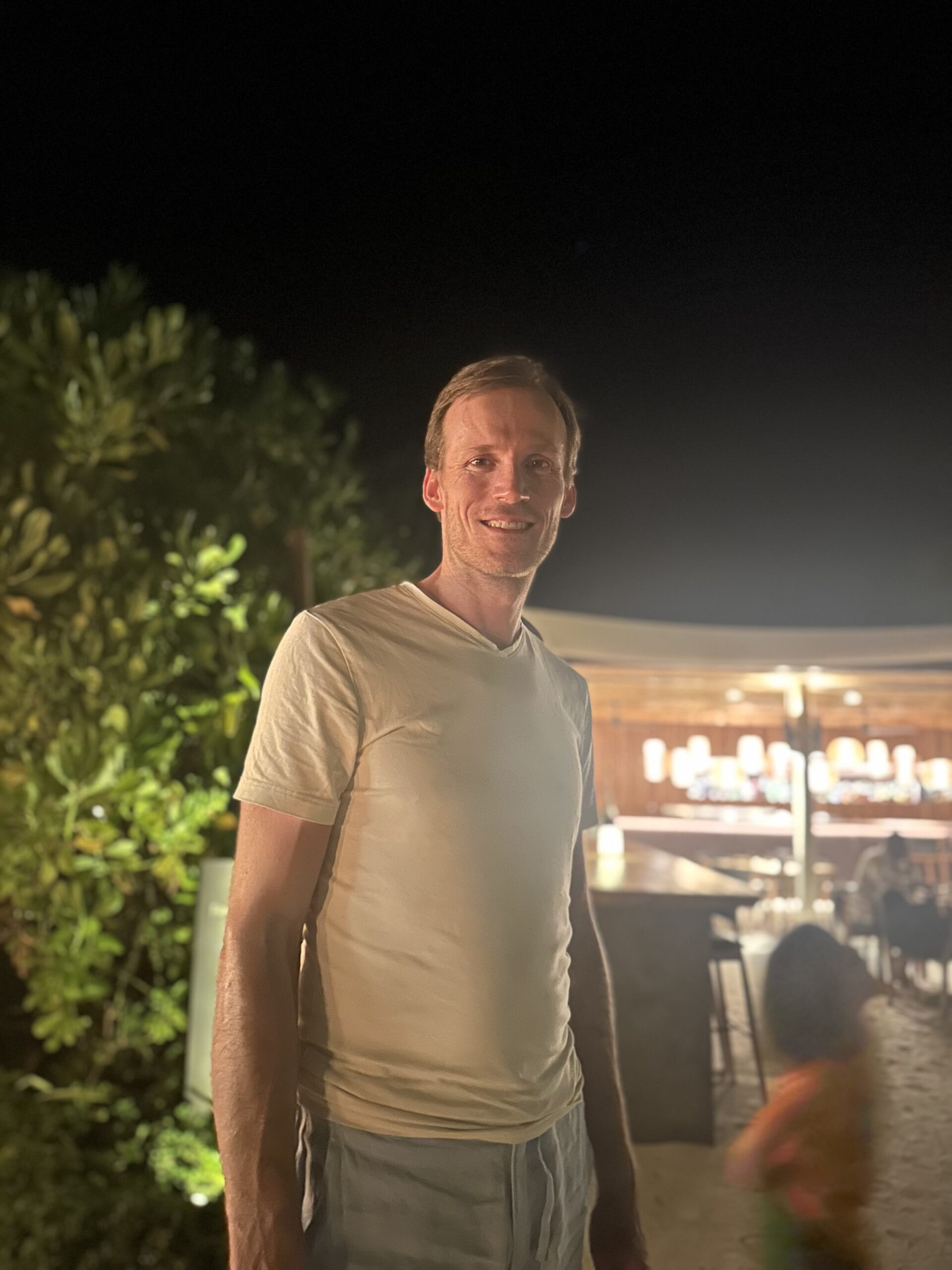 Wouter Mayeur on holidays at night on a beach with lights and a bar in the blurred background