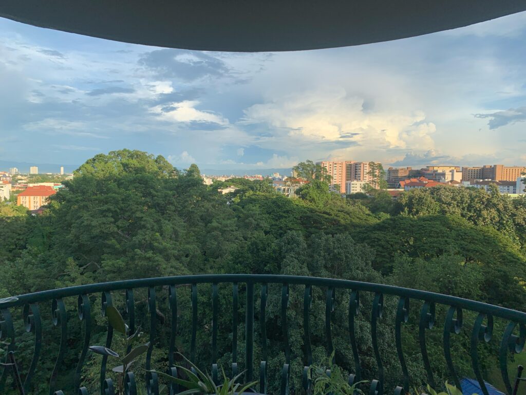View from a balcony of a condo in Chiang Mai, looking out on trees and residential buildings in the distance