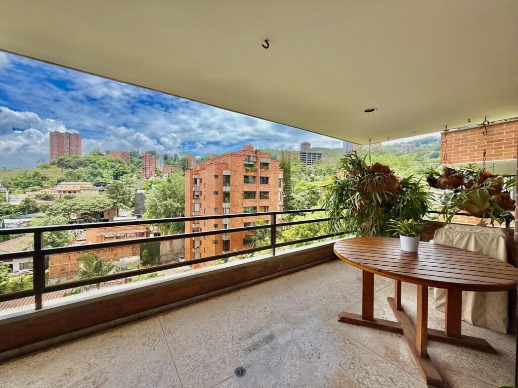 View from a balcony in Medellin onto residential blocks of flats on a hill with lots of trees