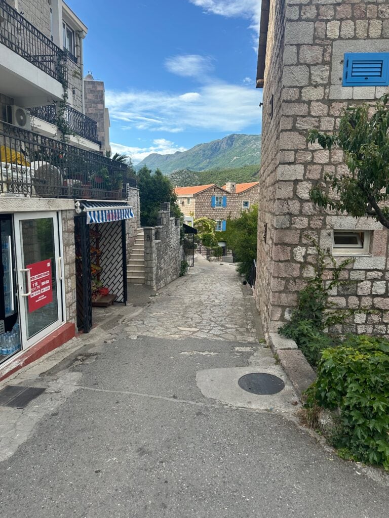 Old town center with stone streets and buildings, green hills in the distance, near Budva, Montenegro