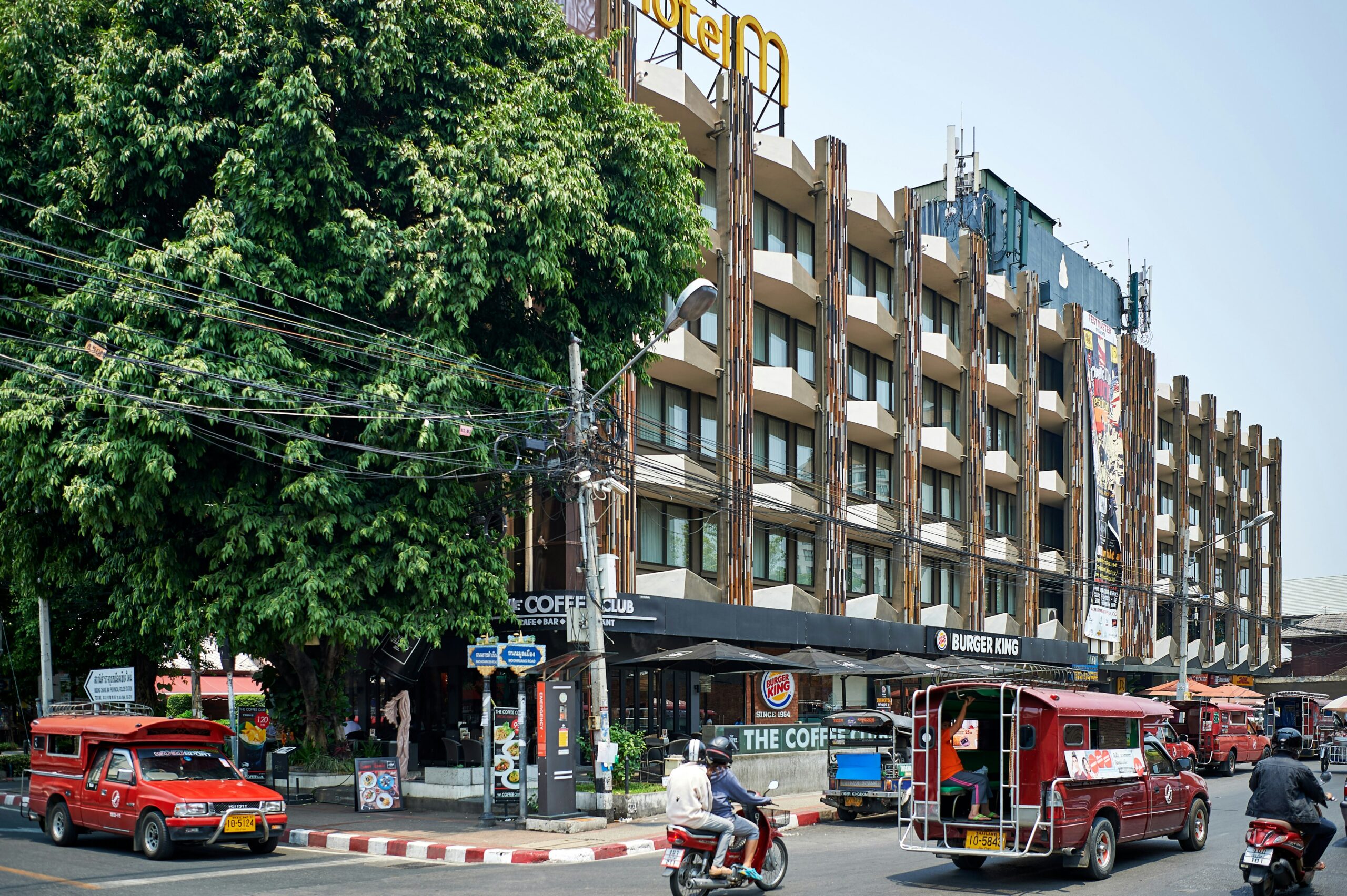Street in central area of Chiang Mai, with cars, shops, restaurants and a large residential block of flats